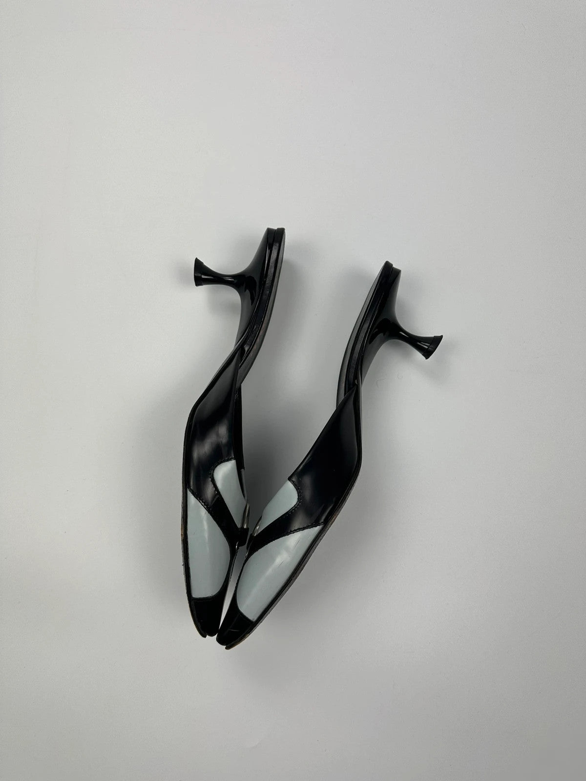 Miu Miu black and blue patent leather pumps with pointy toe and logo detail.