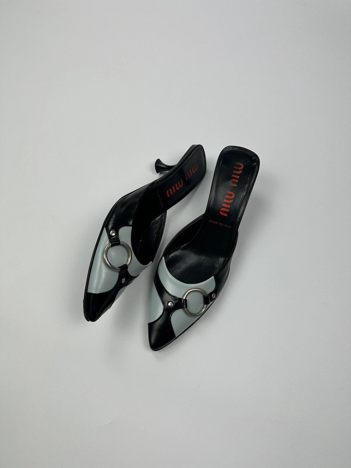 Miu Miu black and blue patent leather pumps with pointy toe and logo detail.