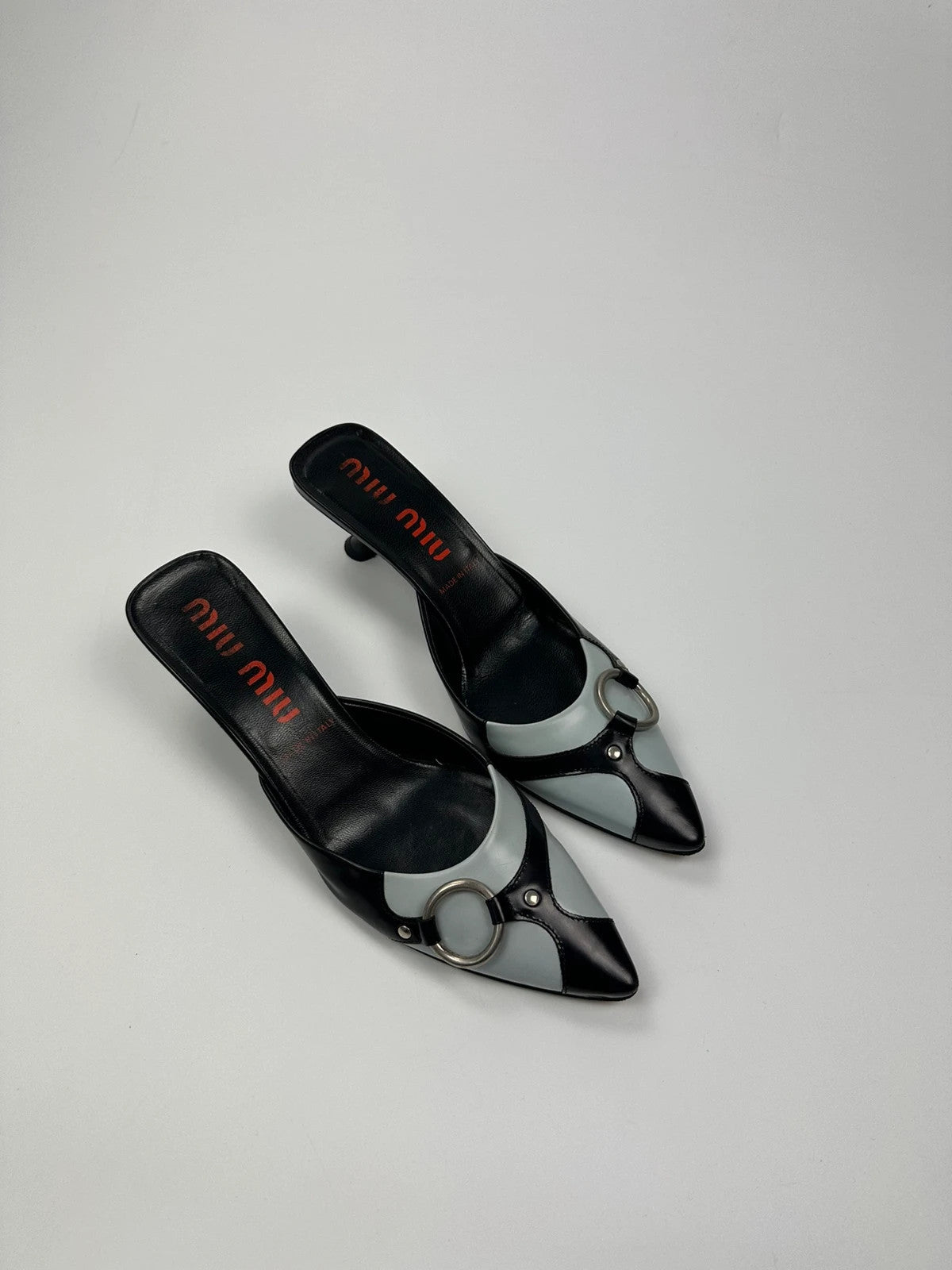 Miu Miu black and blue patent leather pumps with pointy toe and logo detail.