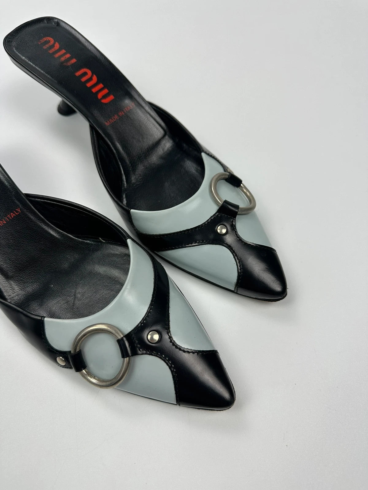 Miu Miu black and blue patent leather pumps with pointy toe and logo detail.