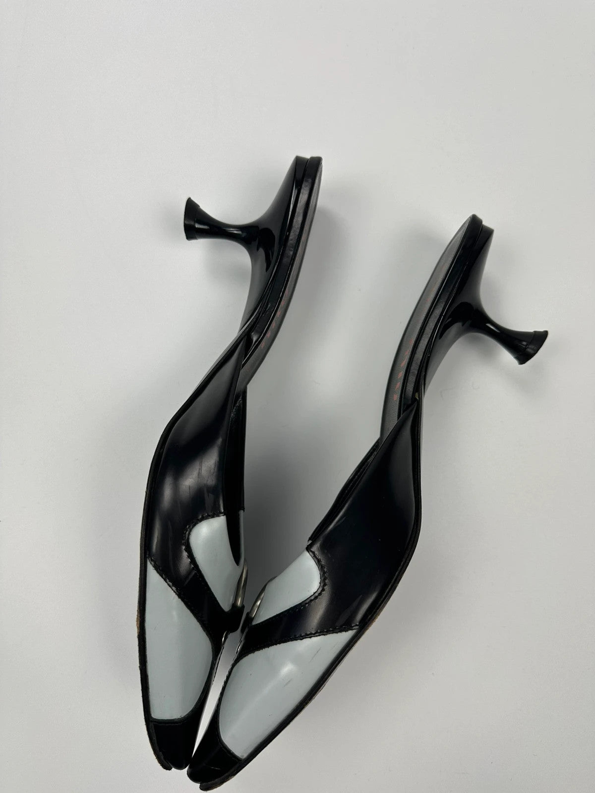 Miu Miu black and blue patent leather pumps with pointy toe and logo detail.