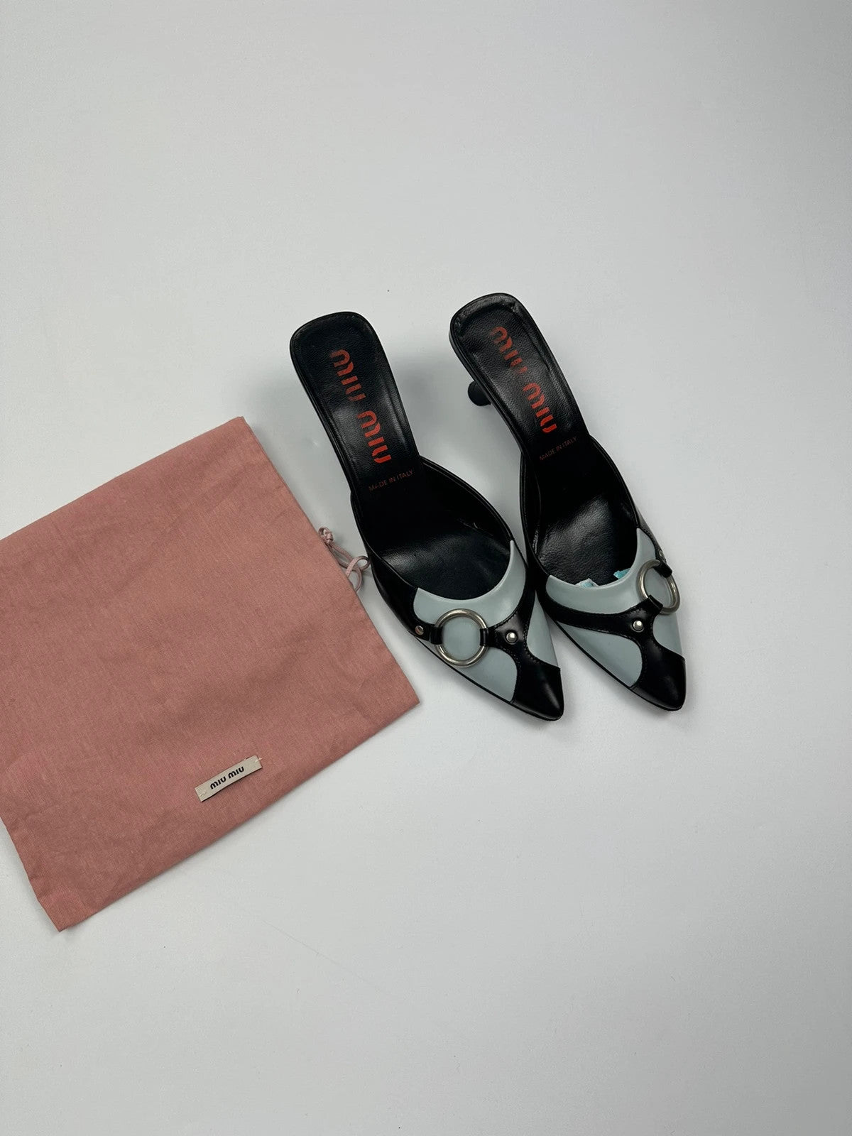 Miu Miu black and blue patent leather pumps with pointy toe and logo detail.