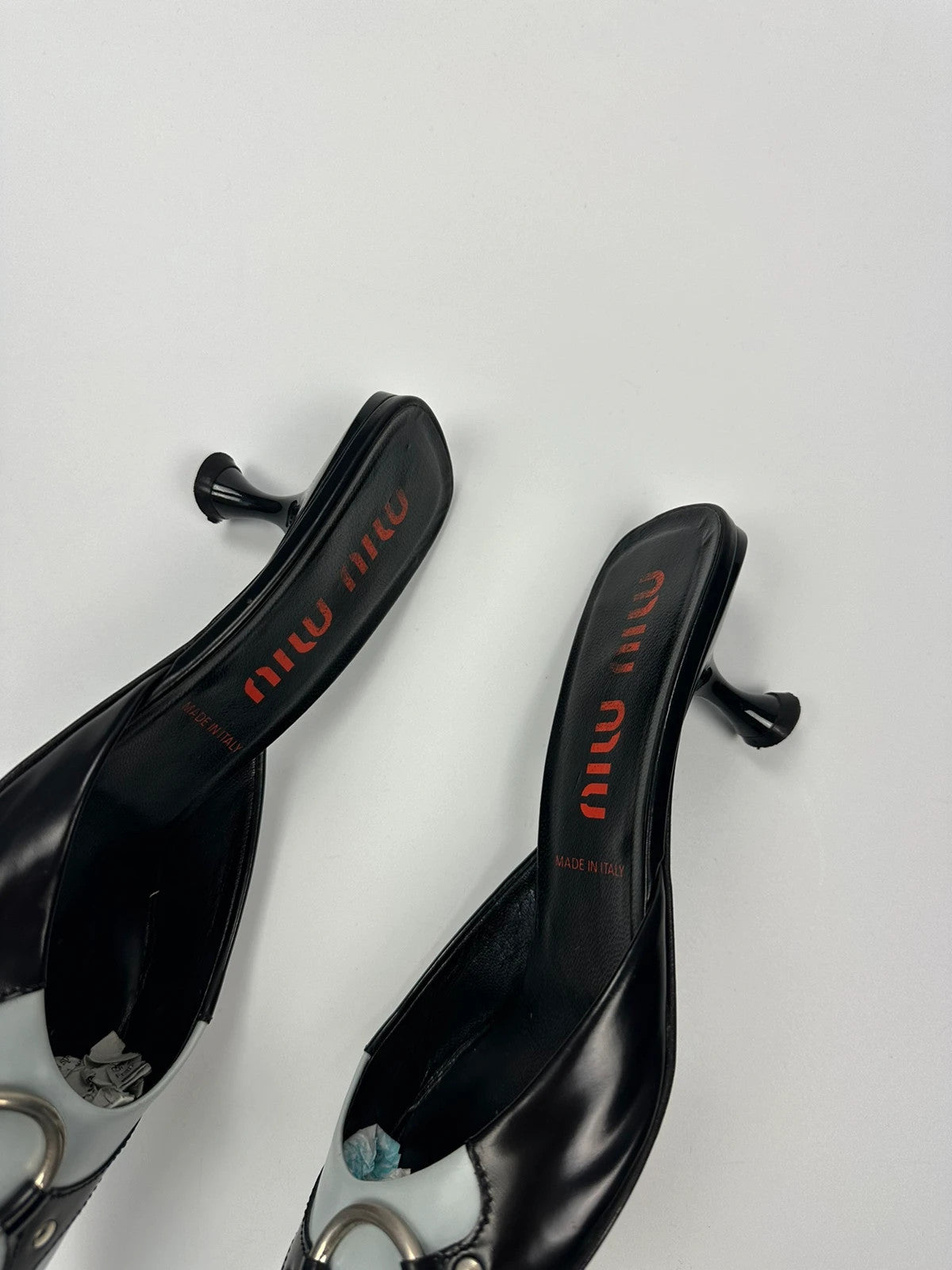 Miu Miu black and blue patent leather pumps with pointy toe and logo detail.