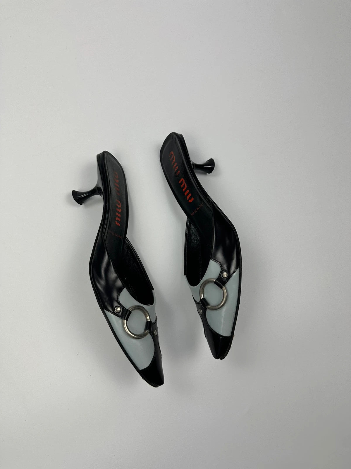 Miu Miu black and blue patent leather pumps with pointy toe and logo detail.