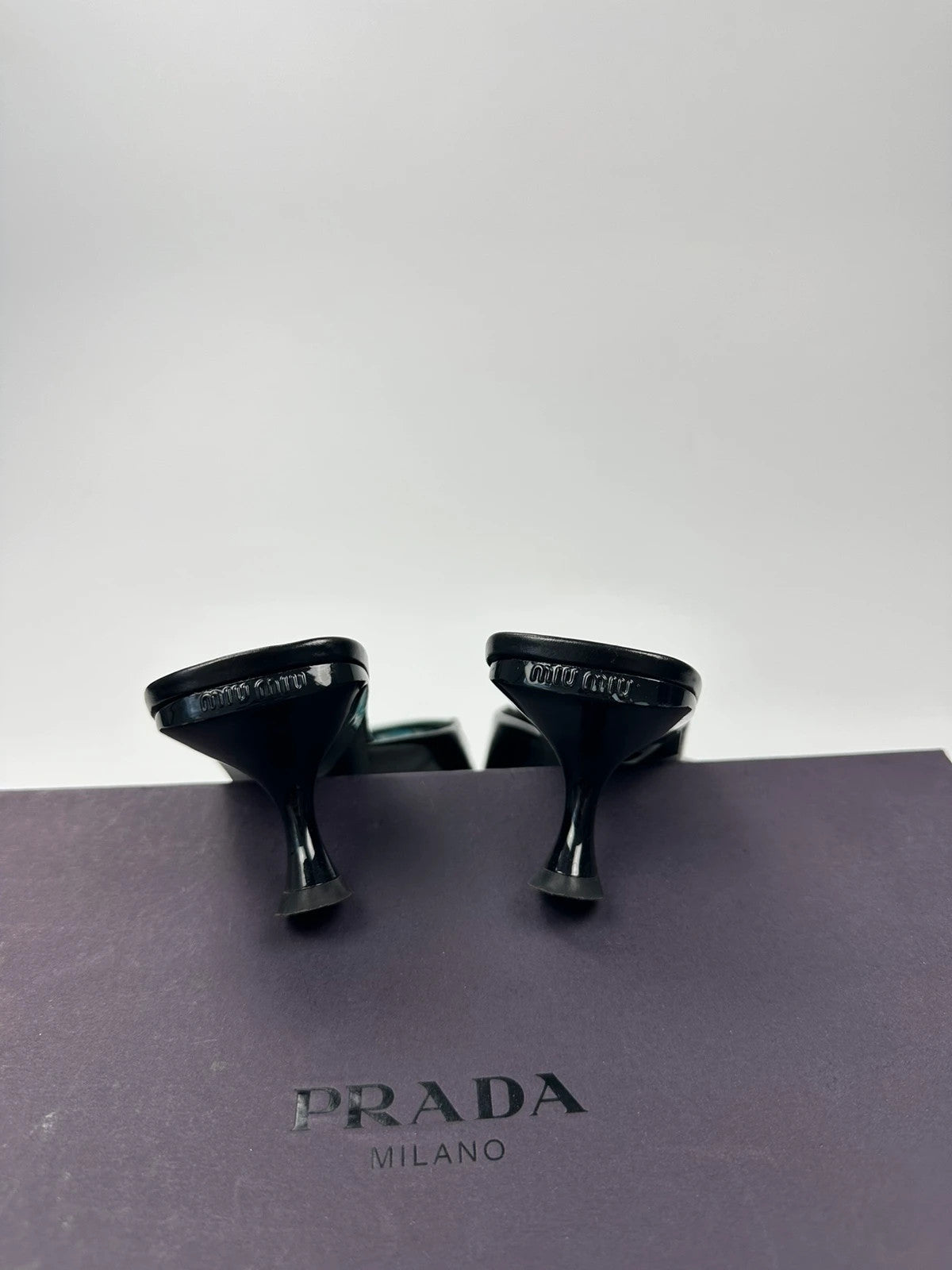 Miu Miu black and blue patent leather pumps with pointy toe and logo detail.