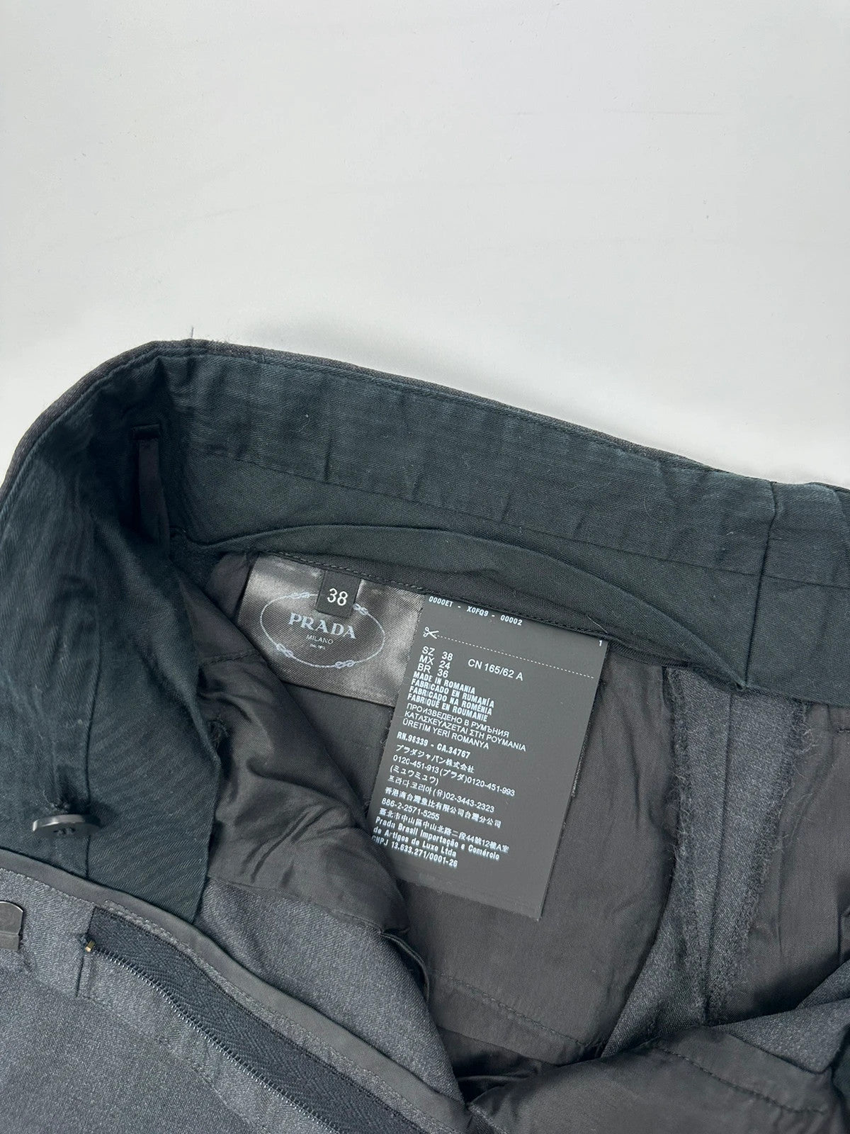 Prada grey wide-leg dress pants with subtle logo detail and luxurious wool material.