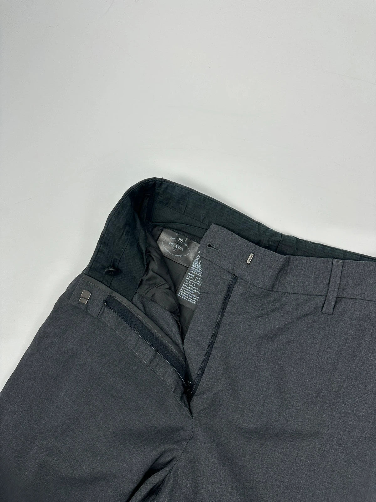 Prada grey wide-leg dress pants with subtle logo detail and luxurious wool material.
