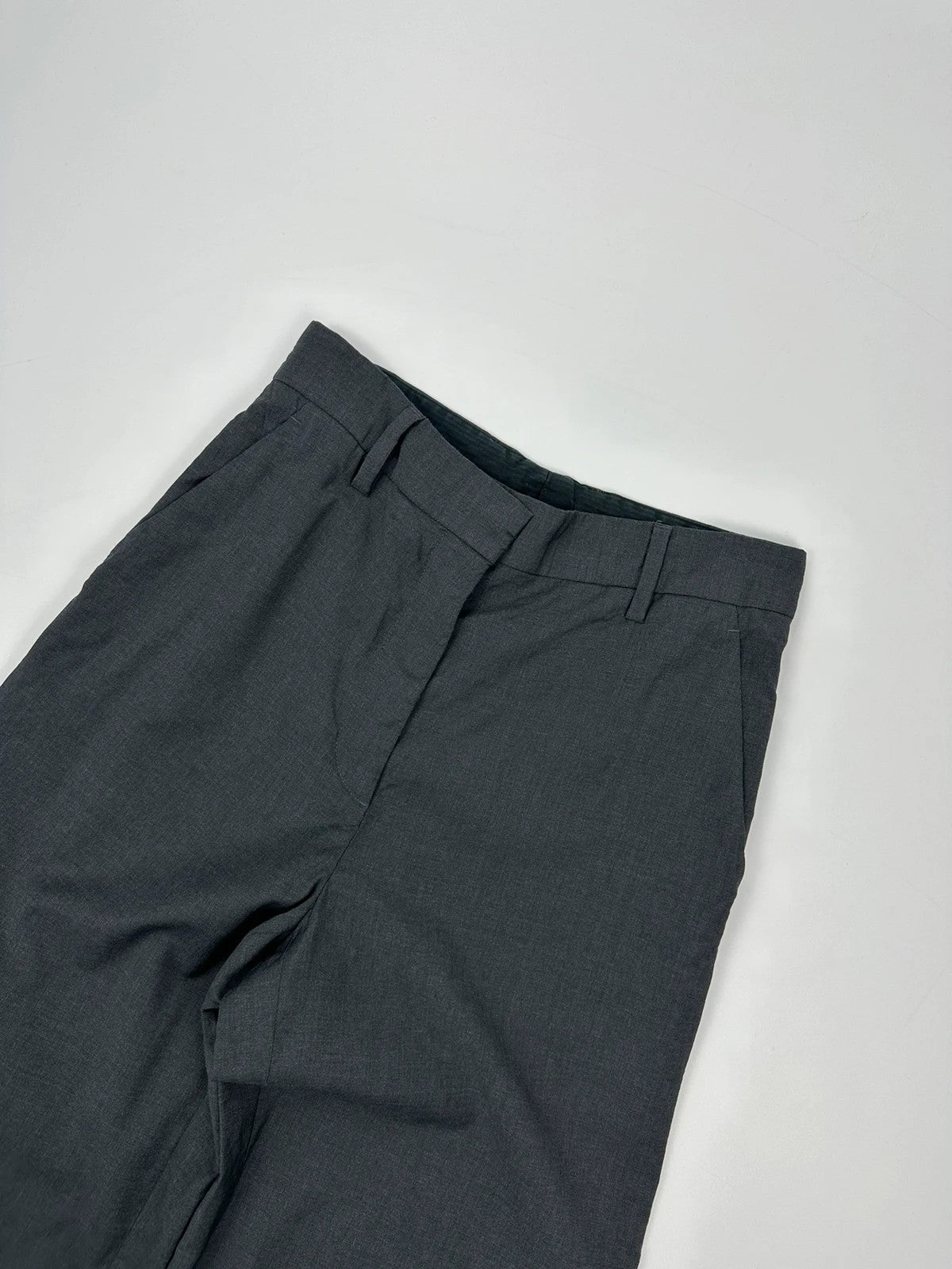 Prada grey wide-leg dress pants with subtle logo detail and luxurious wool material.