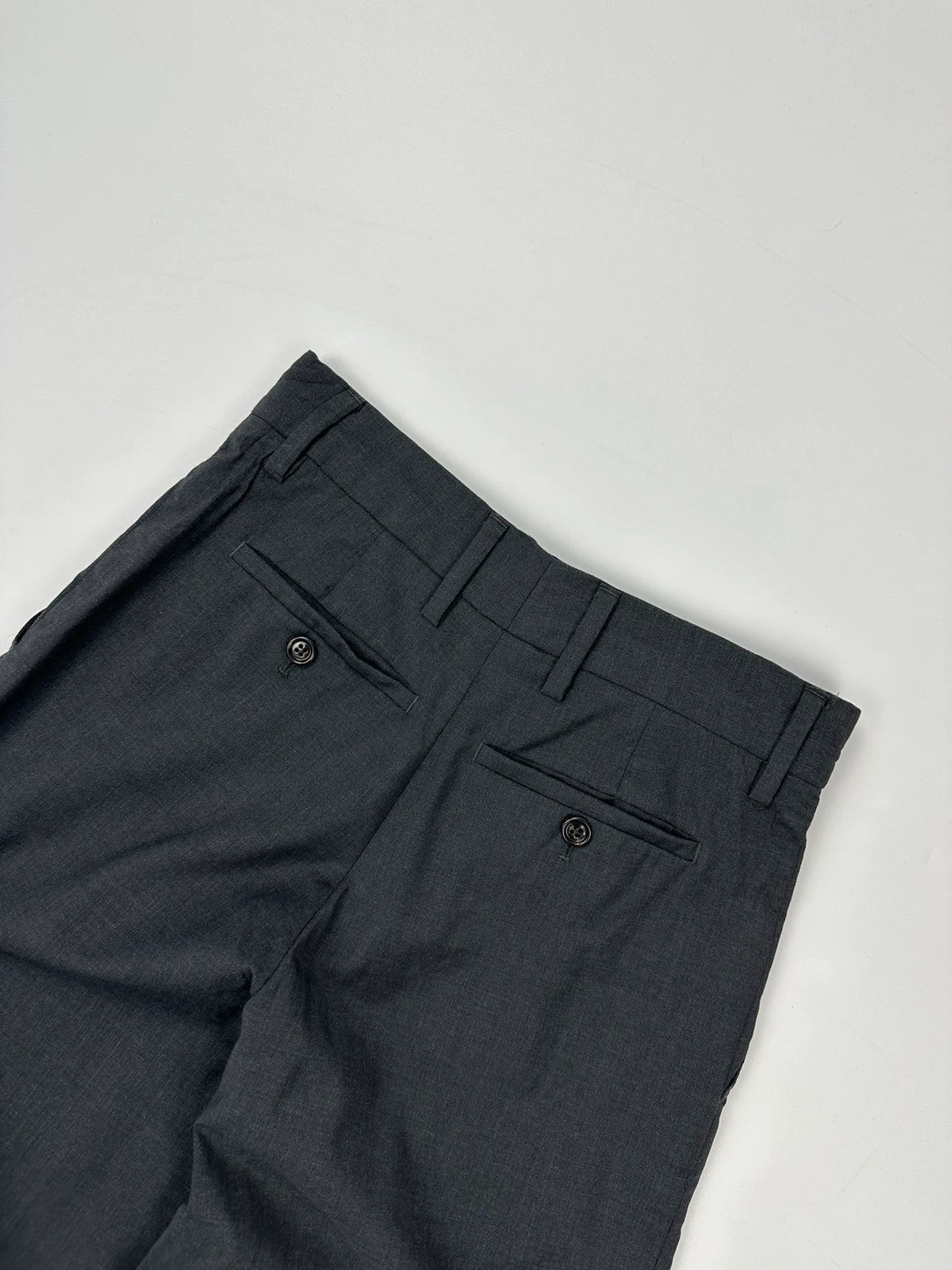 Prada grey wide-leg dress pants with subtle logo detail and luxurious wool material.