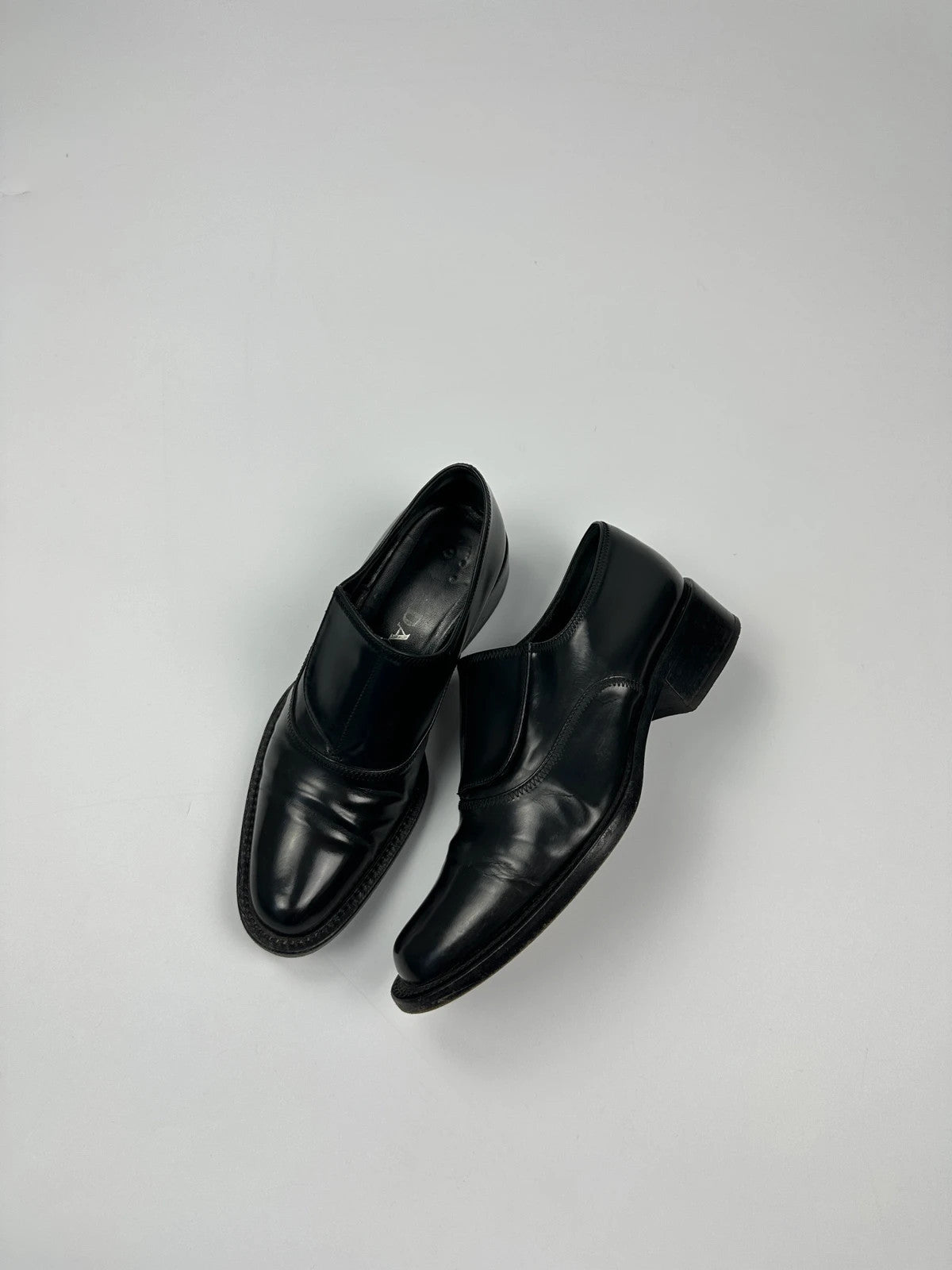Prada black vernis loafers with pointy toe and subtle logo detailing.