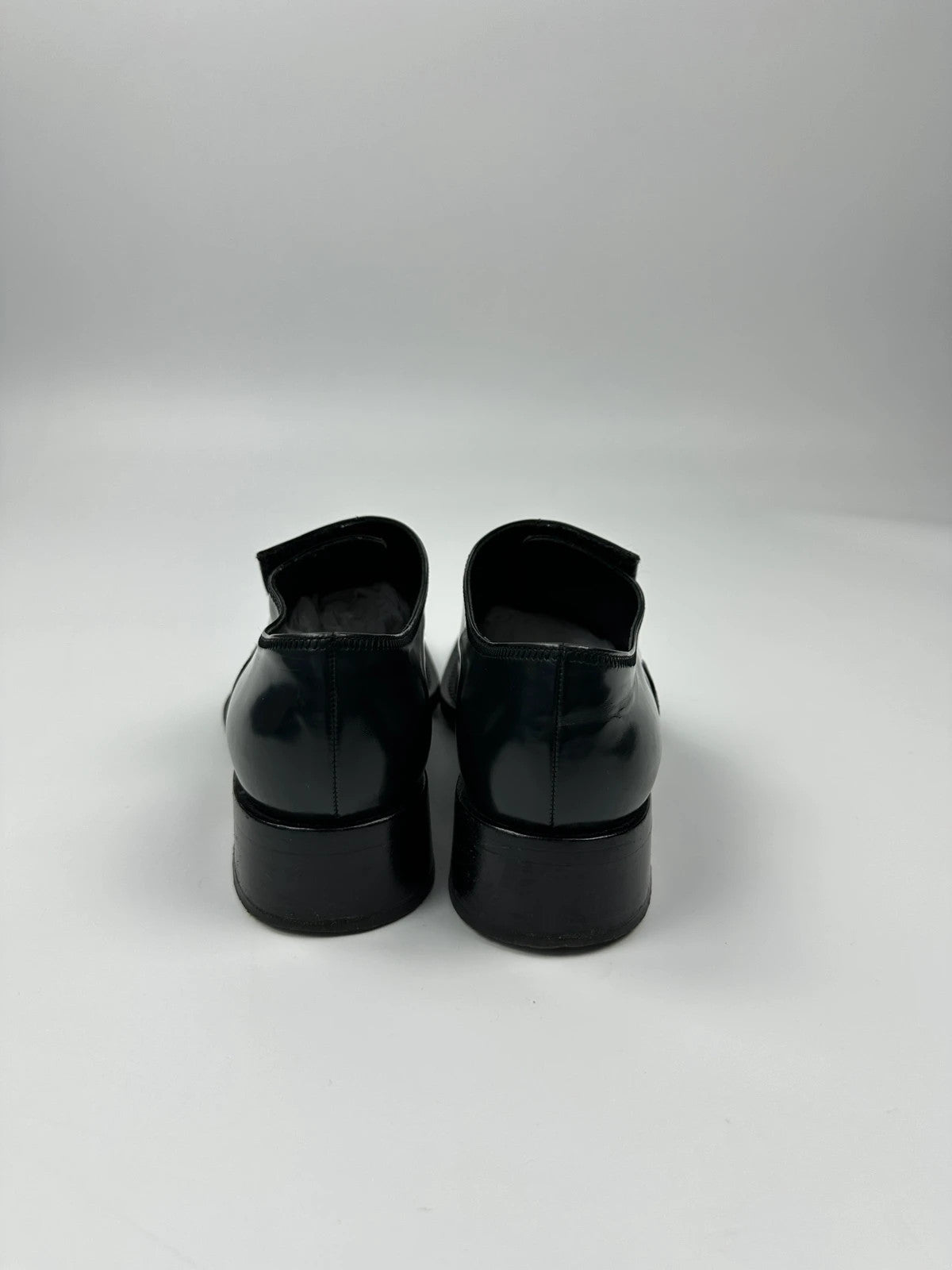 Prada black vernis loafers with pointy toe and subtle logo detailing.