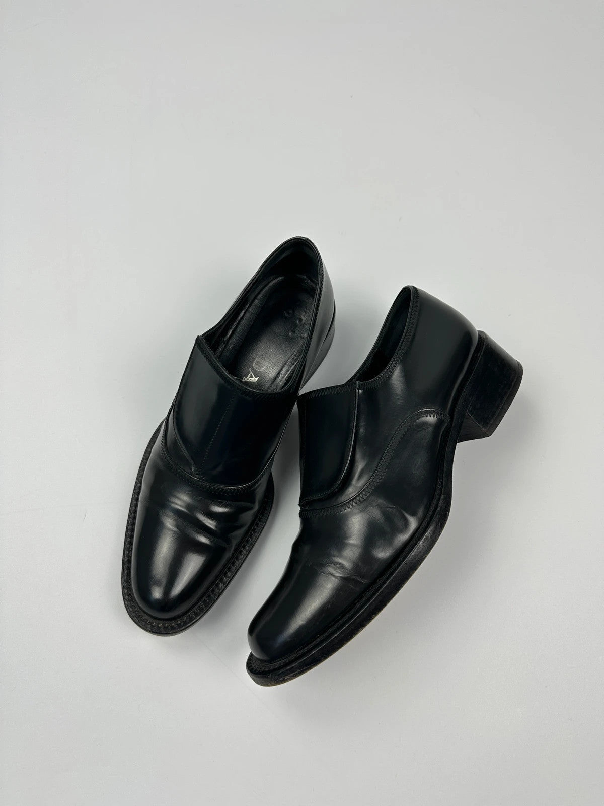 Prada black vernis loafers with pointy toe and subtle logo detailing.