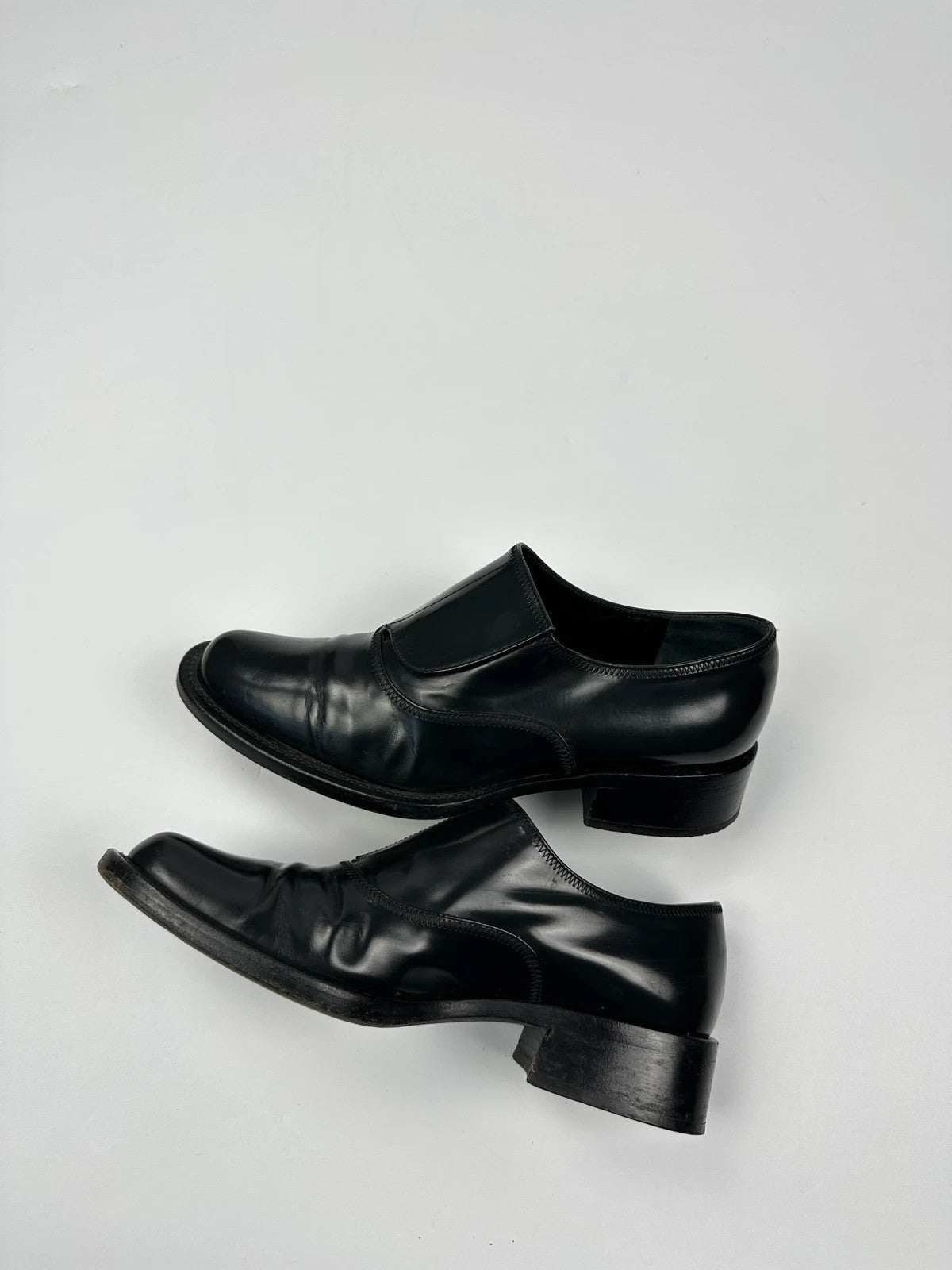 Prada black vernis loafers with pointy toe and subtle logo detailing.