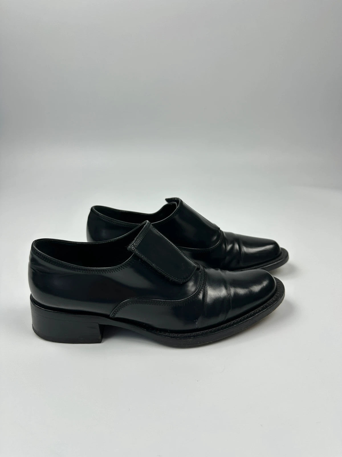 Prada black vernis loafers with pointy toe and subtle logo detailing.