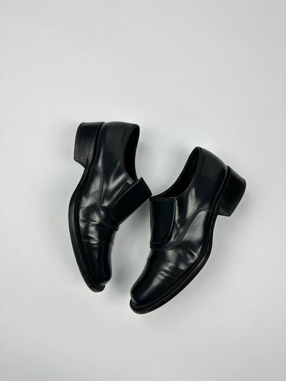 Prada black vernis loafers with pointy toe and subtle logo detailing.