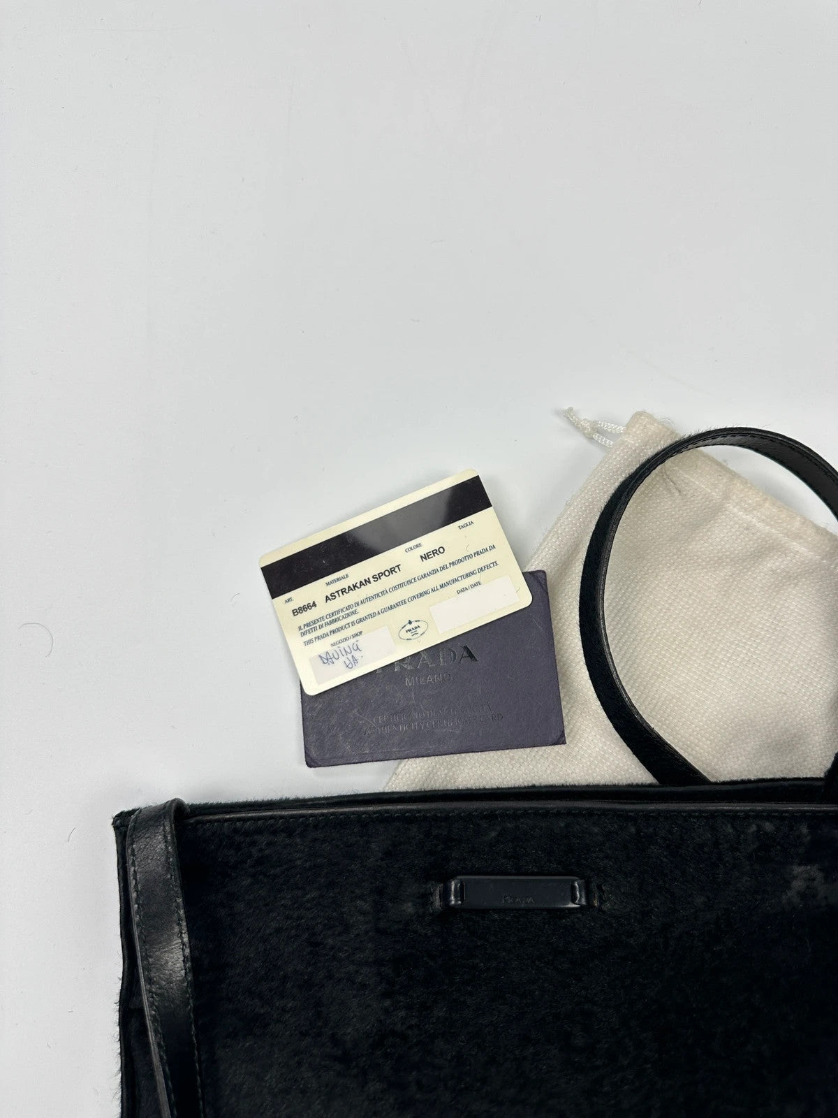 Prada black leather crossbody bag with fur accents and embossed logo.