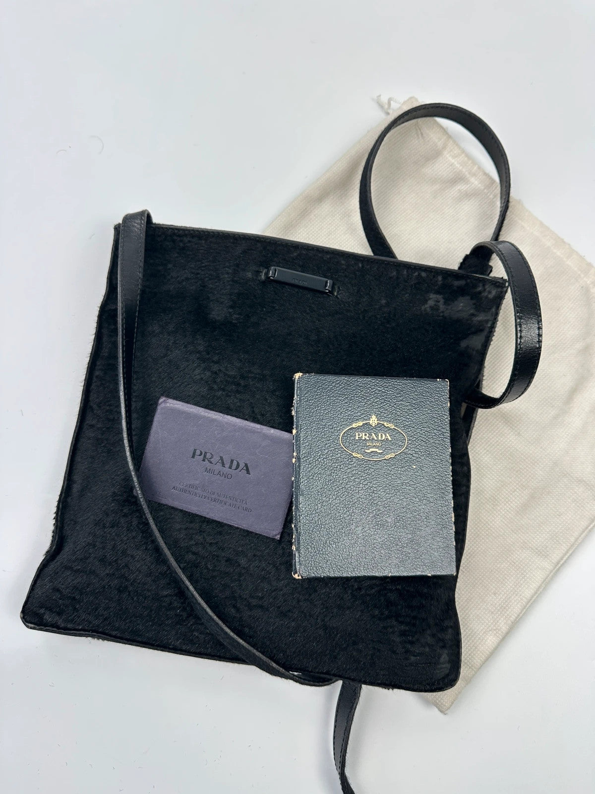 Prada black leather crossbody bag with fur accents and embossed logo.