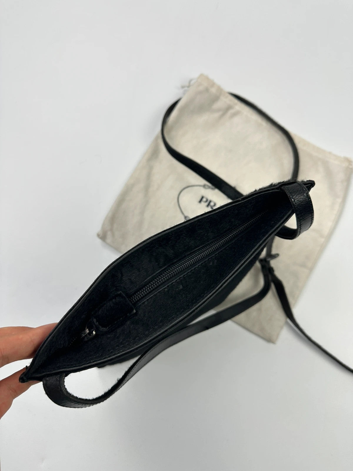 Prada black leather crossbody bag with fur accents and embossed logo.