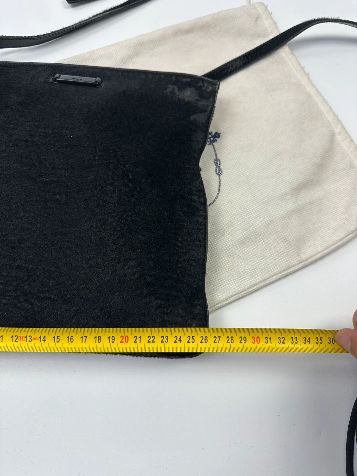 Prada black leather crossbody bag with fur accents and embossed logo.