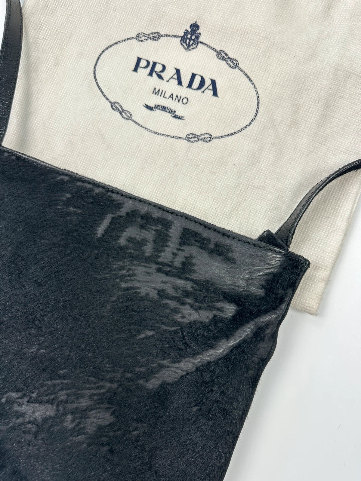 Prada black leather crossbody bag with fur accents and embossed logo.