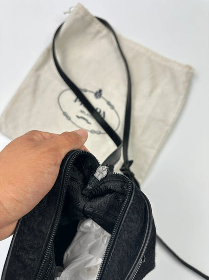 Prada black leather crossbody bag with fur accents and embossed logo.