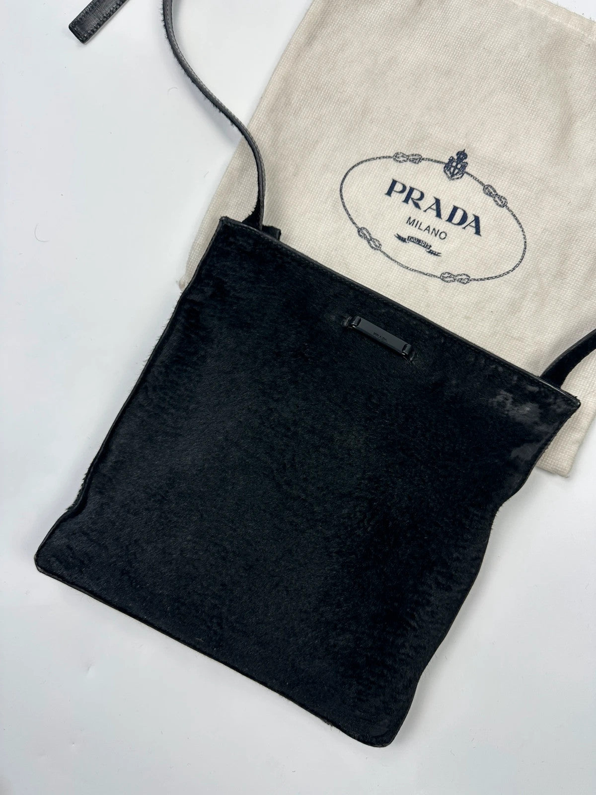 Prada black leather crossbody bag with fur accents and embossed logo.