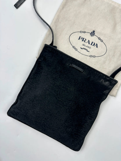 Prada black leather crossbody bag with fur accents and embossed logo.