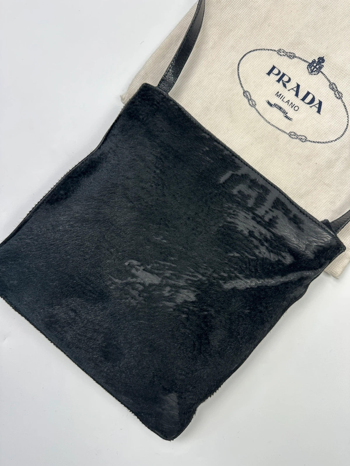 Prada black leather crossbody bag with fur accents and embossed logo.