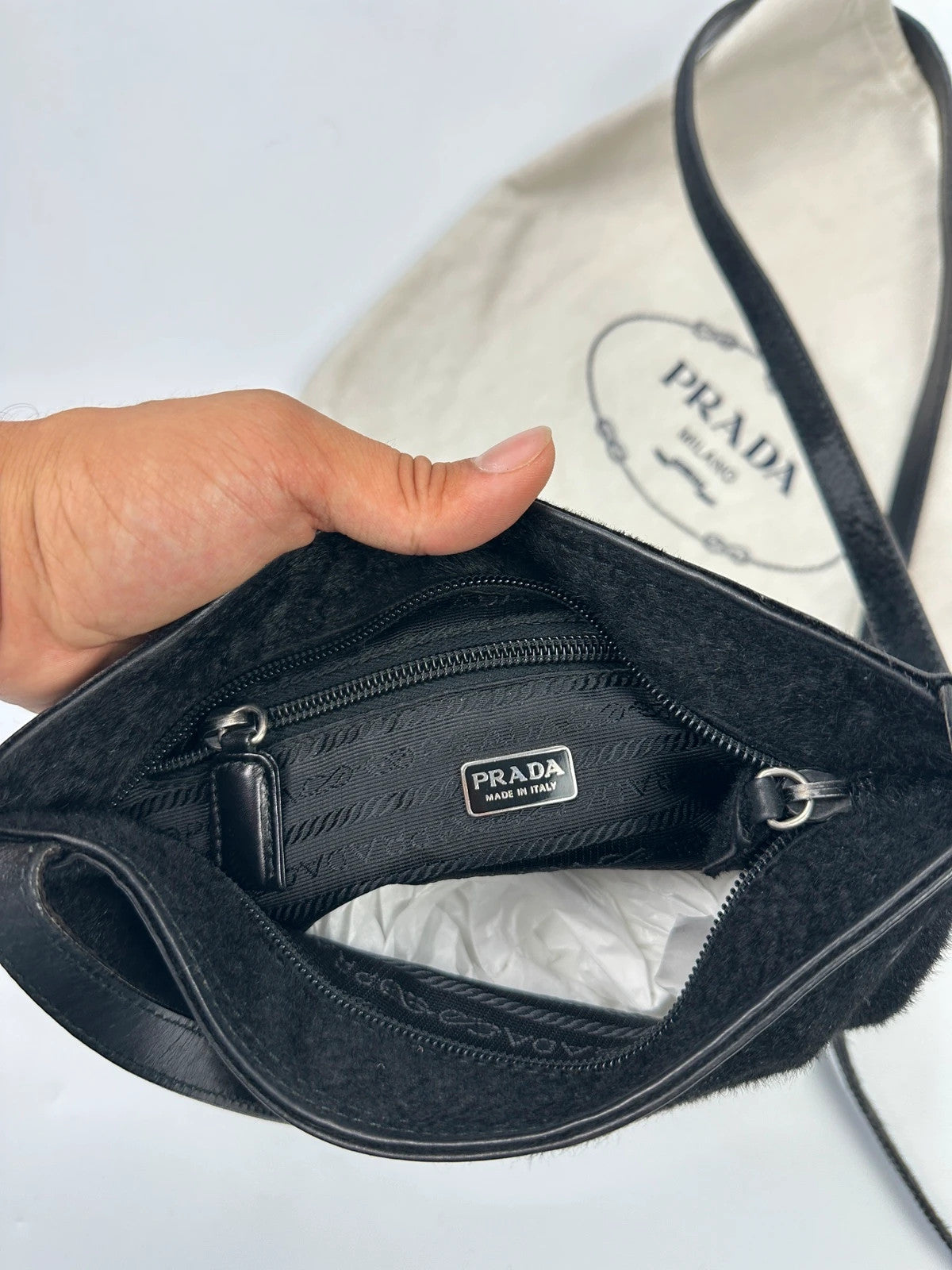 Prada black leather crossbody bag with fur accents and embossed logo.