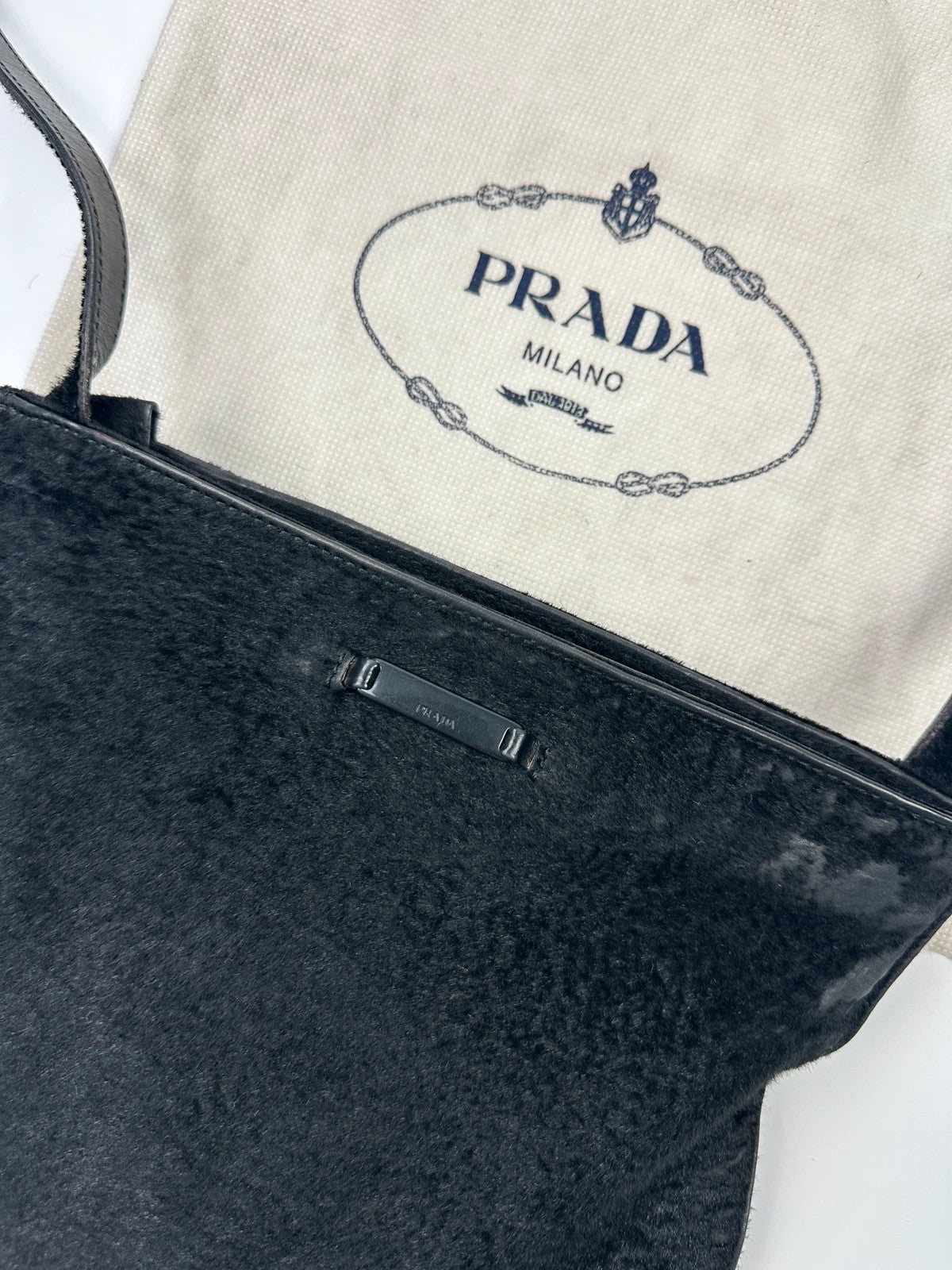 Prada black leather crossbody bag with fur accents and embossed logo.