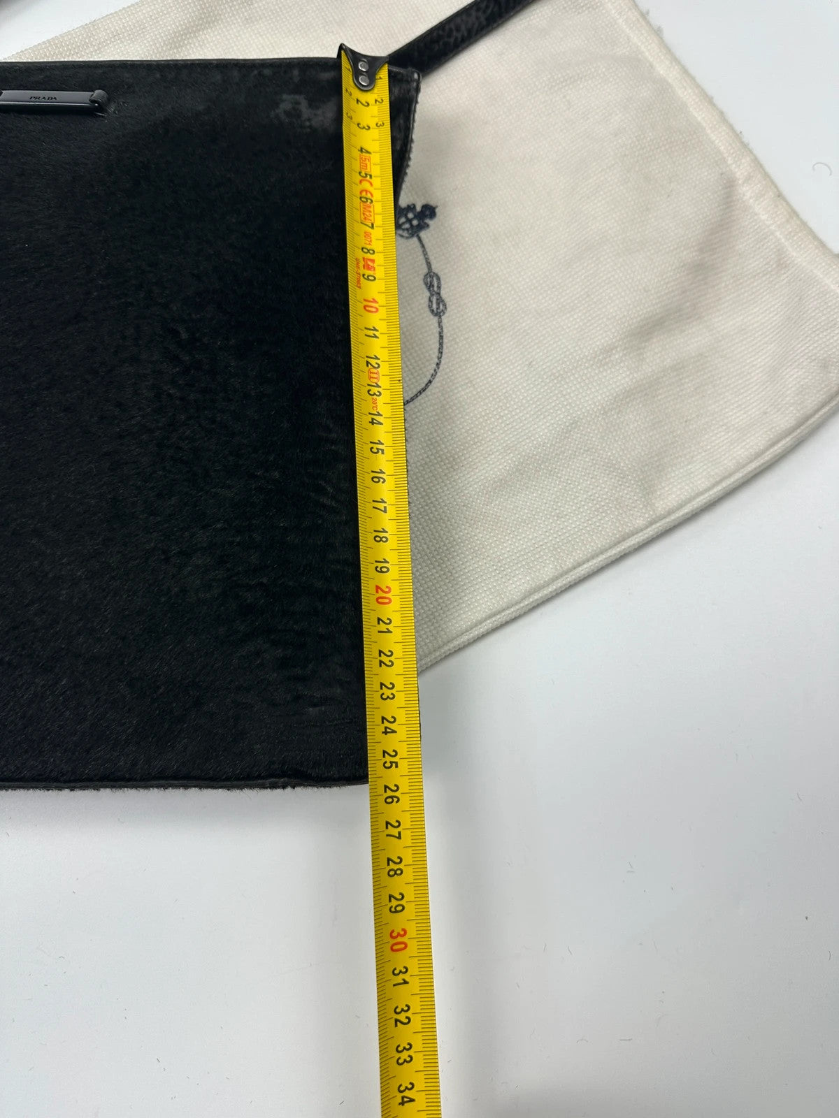 Prada black leather crossbody bag with fur accents and embossed logo.