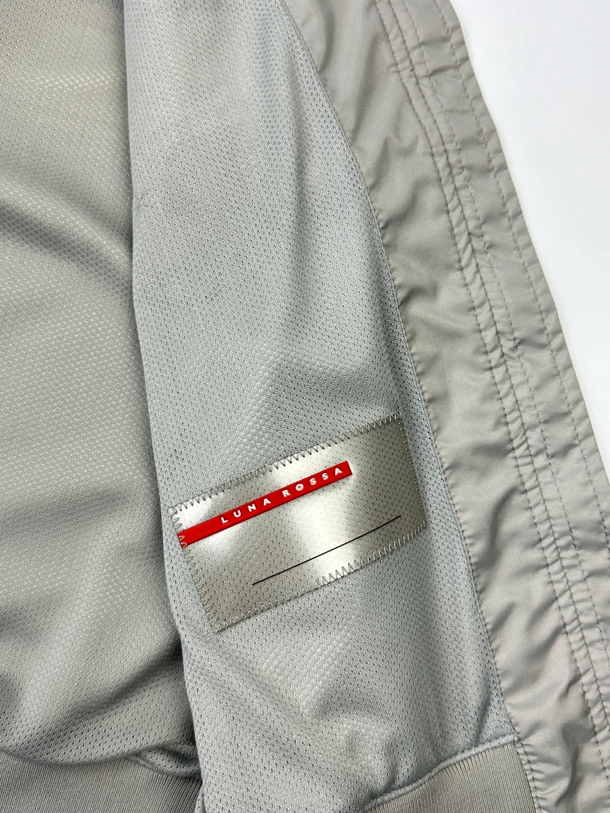 Prada red racing vest with white Luna Rossa logo and minimalist design.