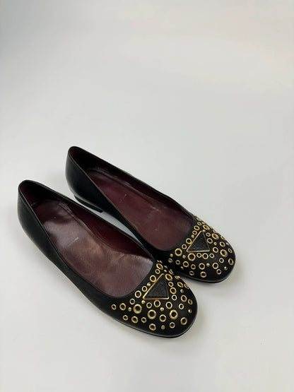 Prada black grained leather loafers with gold eyelets and triangle logo.