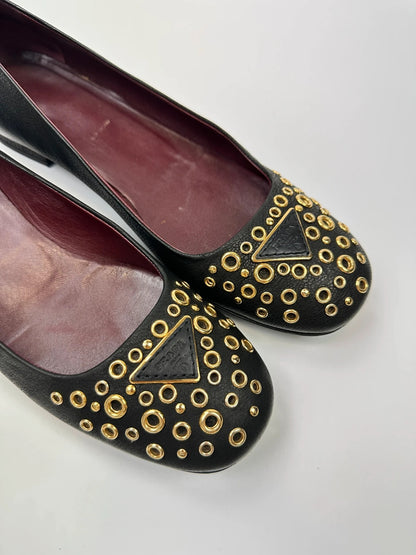 Prada black grained leather loafers with gold eyelets and triangle logo.