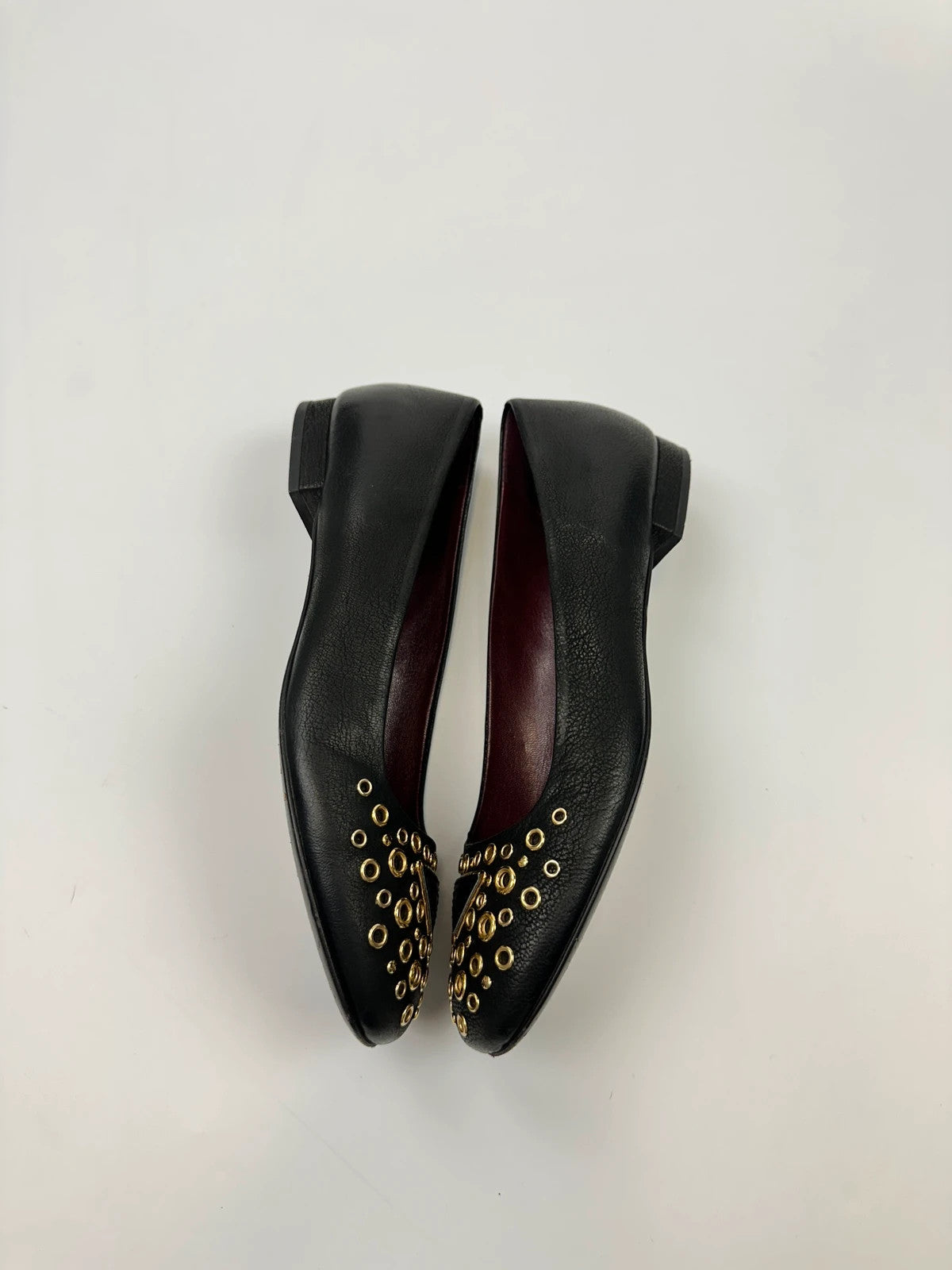 Prada black grained leather loafers with gold eyelets and triangle logo.