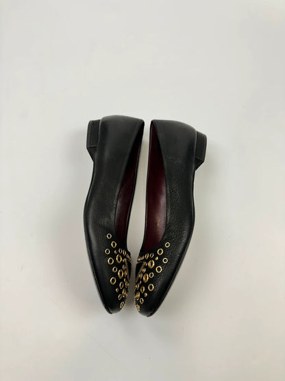 Prada black grained leather loafers with gold eyelets and triangle logo.