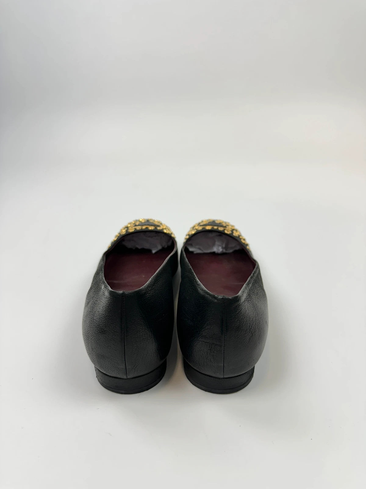 Prada black grained leather loafers with gold eyelets and triangle logo.