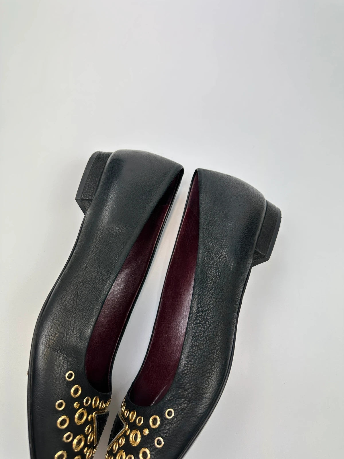 Prada black grained leather loafers with gold eyelets and triangle logo.