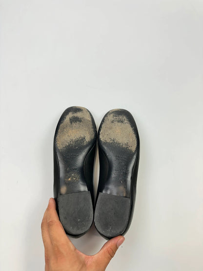 Prada black grained leather loafers with gold eyelets and triangle logo.