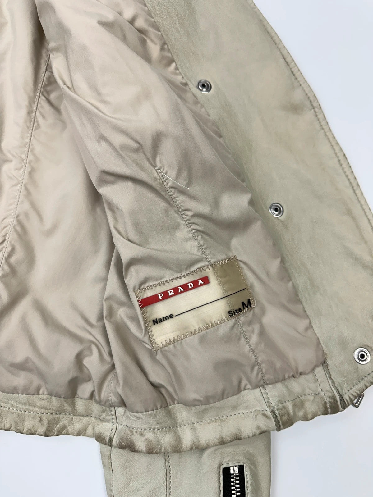 Prada beige leather fitted jacket with multi pockets and logo detailing.