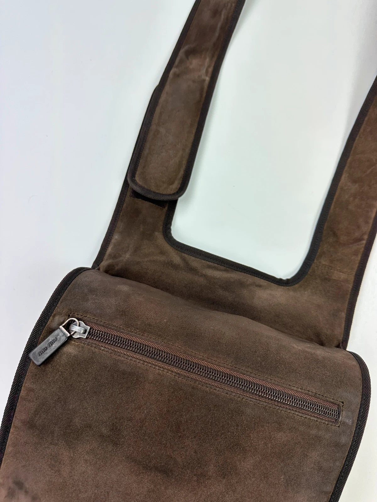 Miu Miu brown suede and mesh crossbody bag with logo detail and vintage design.