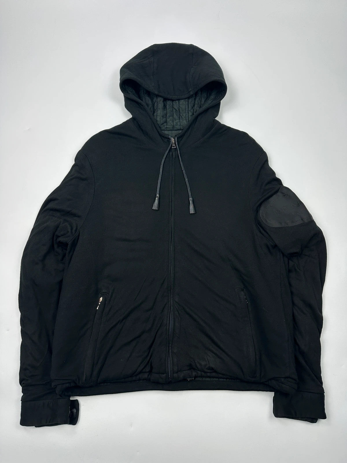 Prada black padded hooded jacket with 90s-inspired patch and braided drawstrings.