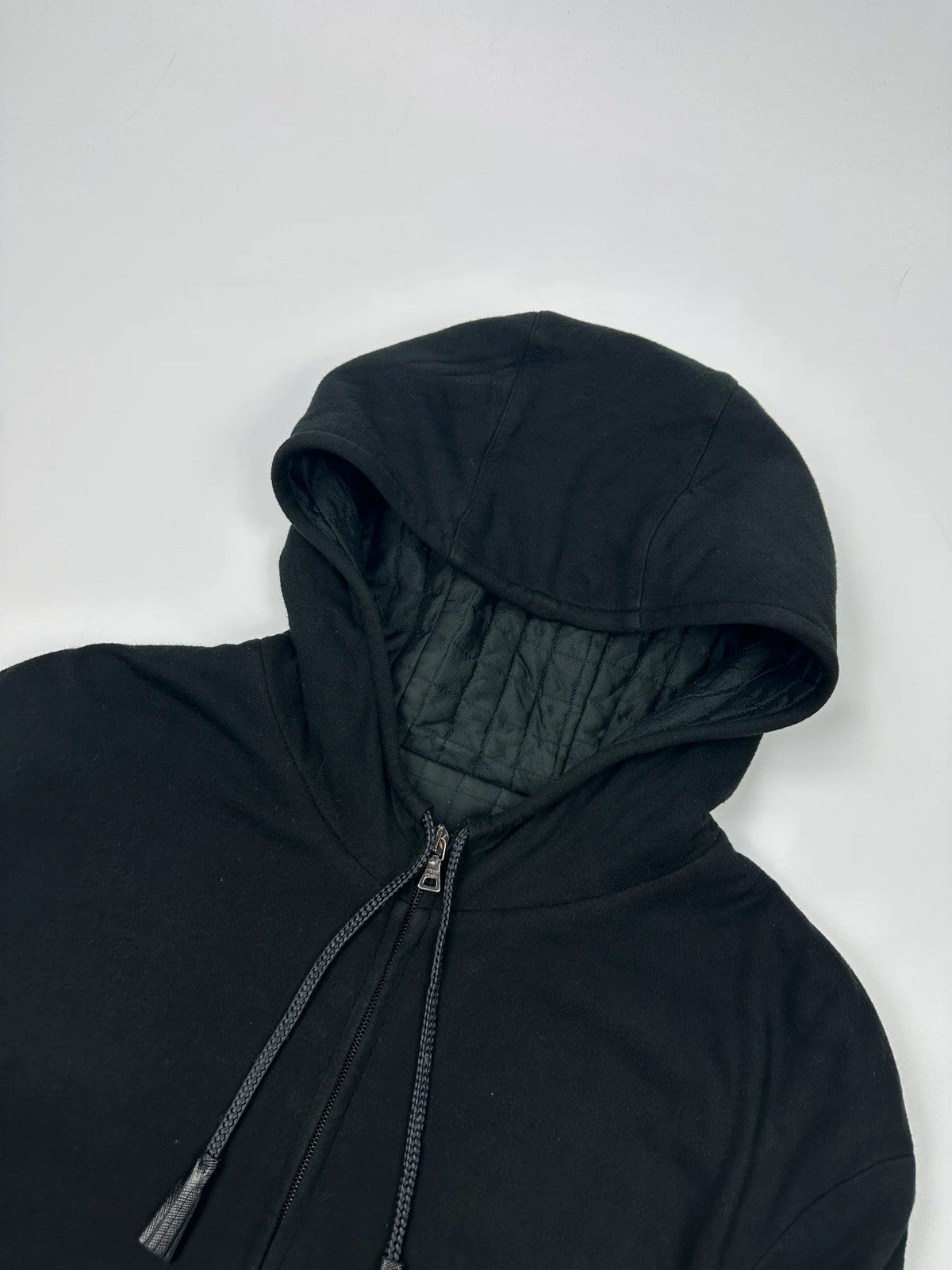 Prada black padded hooded jacket with 90s-inspired patch and braided drawstrings.