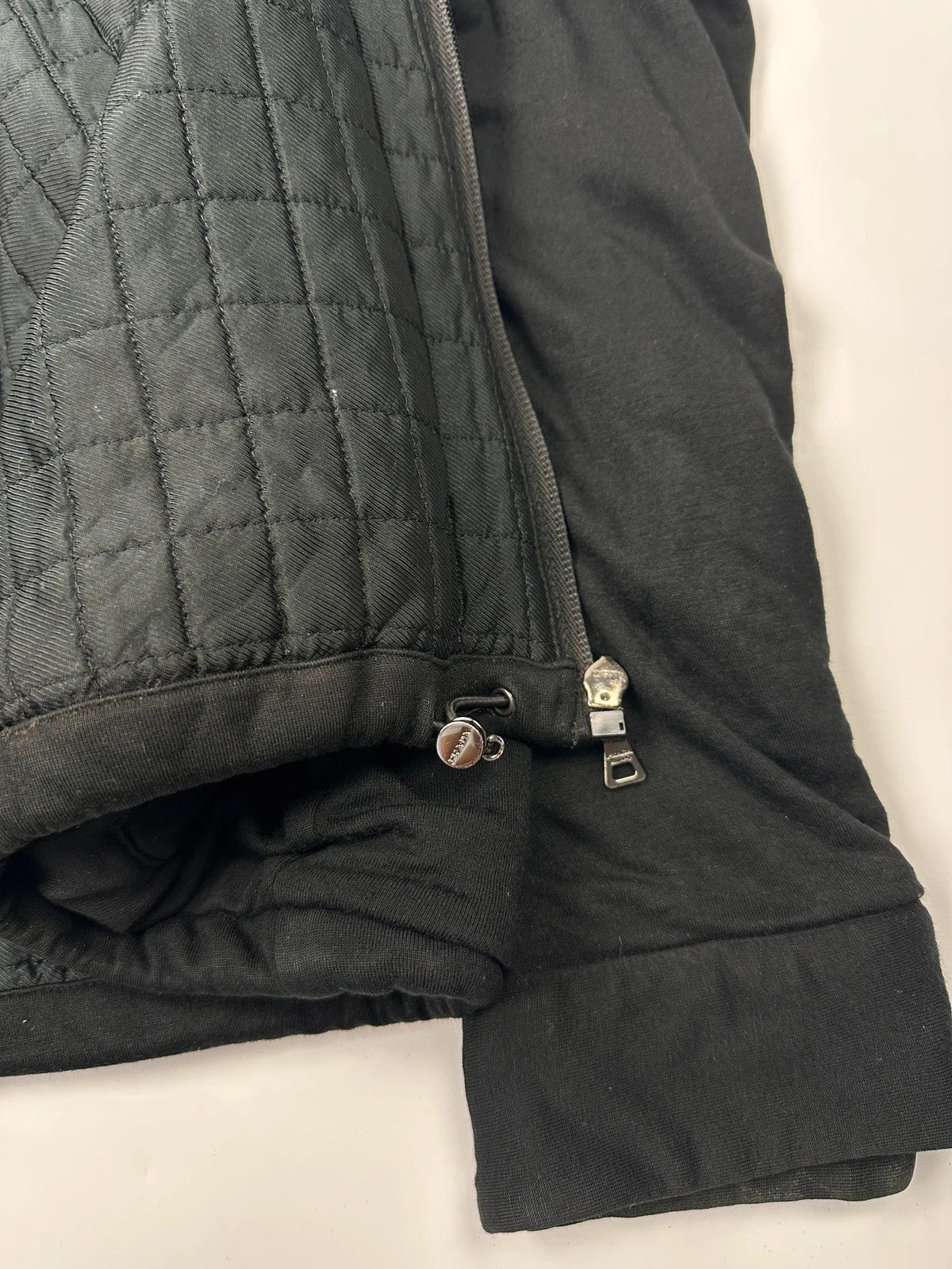 Prada black padded hooded jacket with 90s-inspired patch and braided drawstrings.