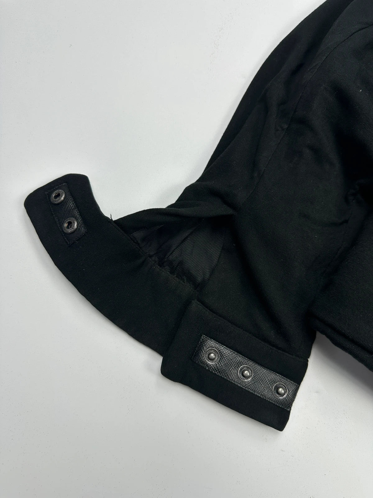 Prada black padded hooded jacket with 90s-inspired patch and braided drawstrings.