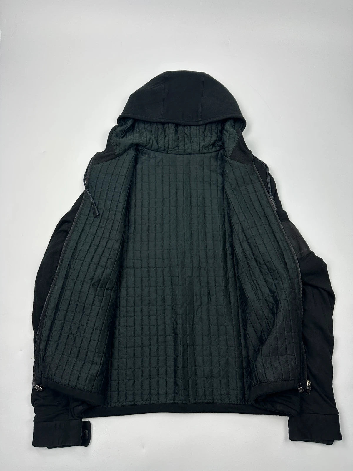 Prada black padded hooded jacket with 90s-inspired patch and braided drawstrings.