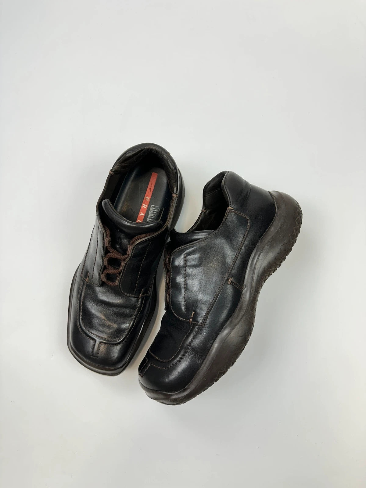 Prada black leather Derby shoes with Vibram sole and Linearossa logo detail.