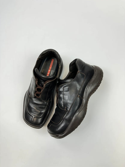 Prada black leather Derby shoes with Vibram sole and Linearossa logo detail.