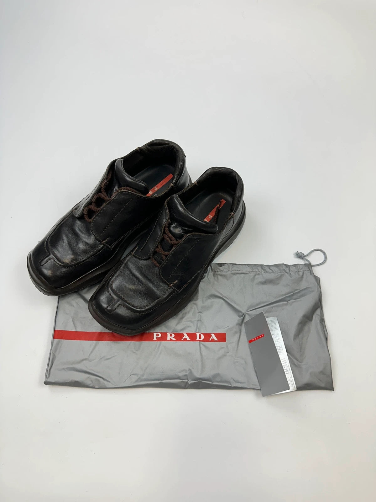 Prada black leather Derby shoes with Vibram sole and Linearossa logo detail.