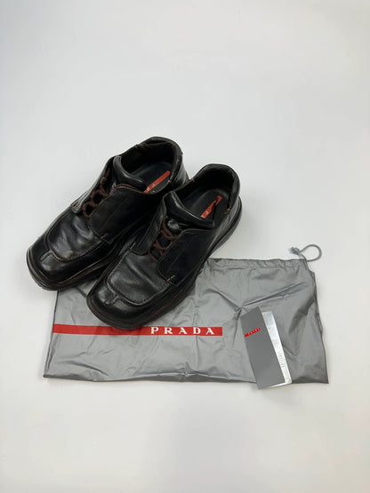 Prada black leather Derby shoes with Vibram sole and Linearossa logo detail.